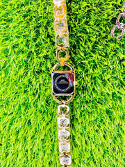 Gold-tone women's midi watch with link chain band on vibrant green grass background