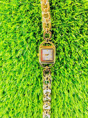 Chic gold midi women's watch with chain link bracelet on vibrant green grass background