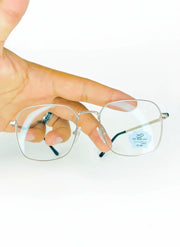 Hand holding slim silver frame blue light blocking glasses with clear rectangular lenses