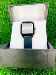 Universe Point classic black square dial watch with minimalist design on white cushion in black box on green grass